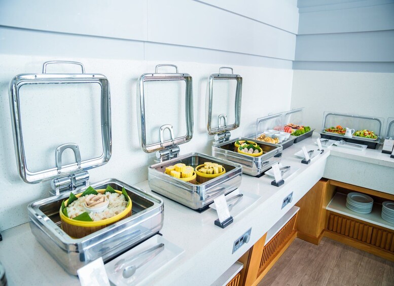 Een buffetopstelling met diverse gerechten in metalen bakken, waarvan sommige afgesloten en andere open. 4