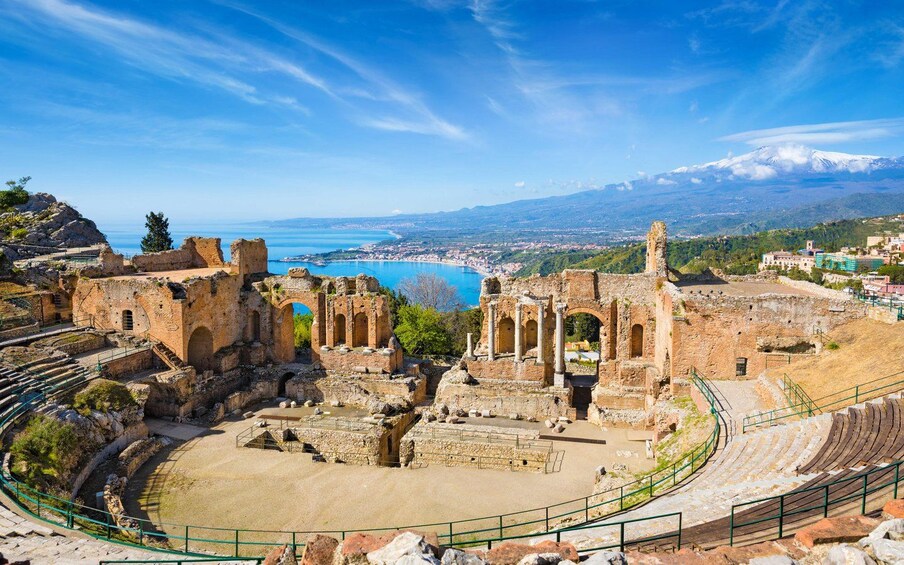 Ancient ruins with a theater, a coastal view, and a distant mountain range. 5