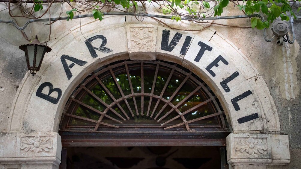 An arched entrance with the inscription 'BAR VITELLI' above it. 2