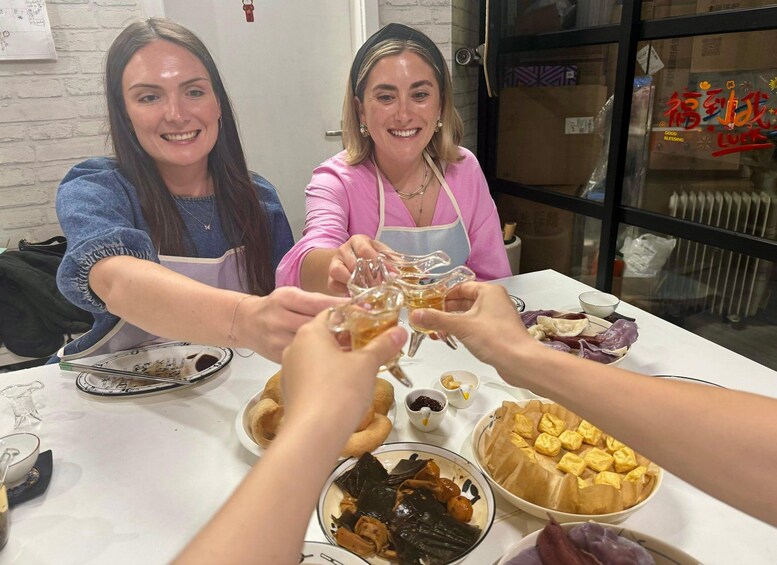 Two people toasting with a glass of drink at a table with various dishes. 5