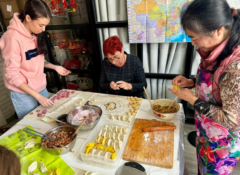 Three people preparing food at a table with various ingredients and utensils. 1