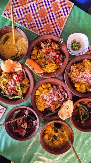 Une variété de plats servis dans des pots en argile sur une table recouverte d’une nappe verte. 2