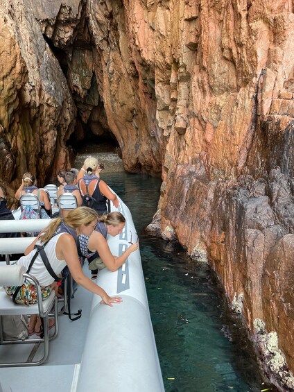 Un grupo de personas en un bote cerca de acantilados rocosos. 5