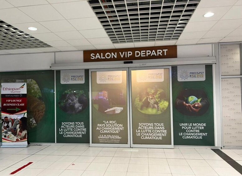 A Salon VIP Depart entrance with a sign above it. There are four large posters with text and images related to climate change. 4