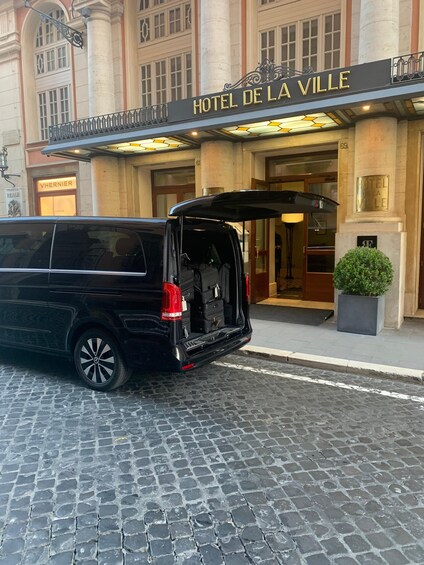 Una camioneta negra estacionada frente al Hotel de la Ville, con las puertas traseras abiertas. 1