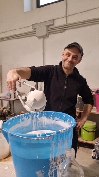 A person pouring a white substance into a blue bucket. 5