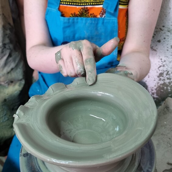 A person shaping a clay pot on a pottery wheel. 2