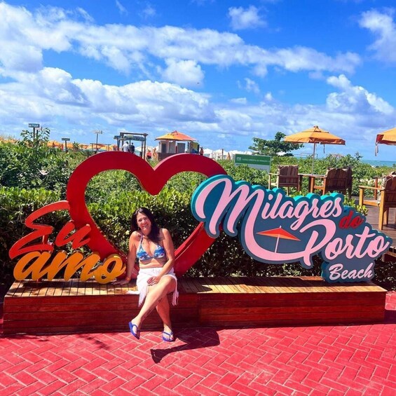 Una mujer sentada frente a un cartel que dice 'Milagres do Porto Beach'. 4