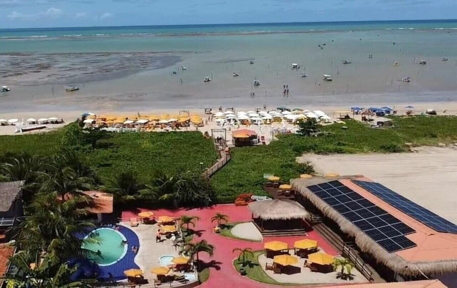 Un complejo turístico en la playa con piscina, sillones de descanso y panel solar. 1
