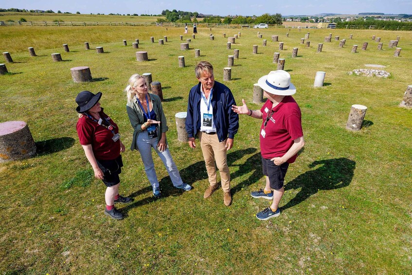 A group of people standing in a grassy field with stone markers. 2