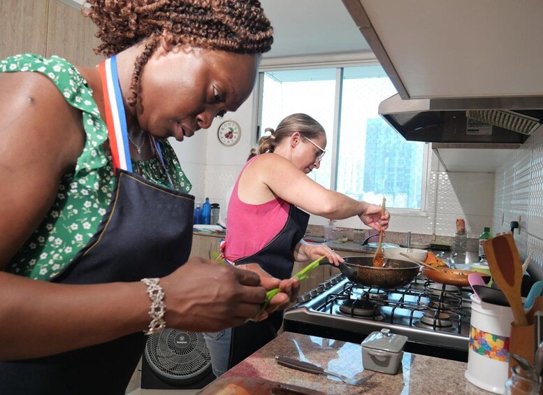 Dos personas cocinando en una cocina moderna con estufa, ollas y varios utensilios. 4