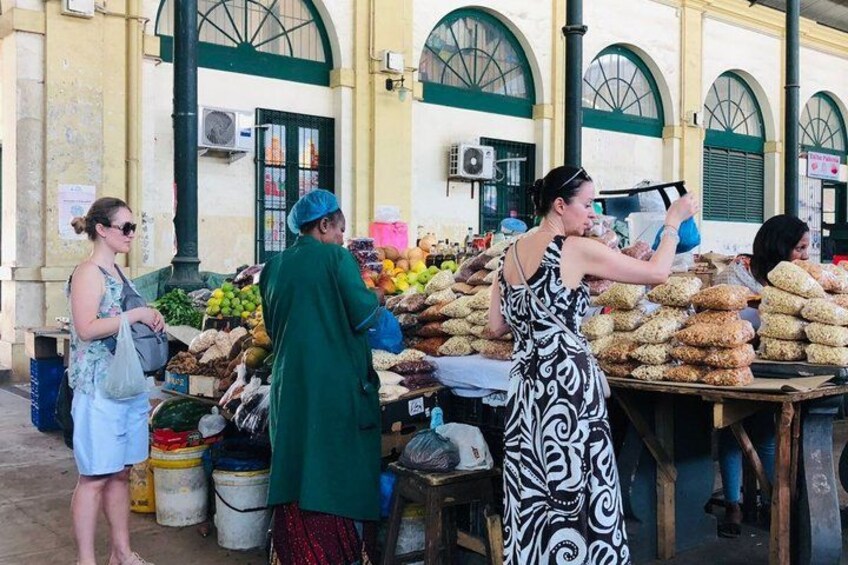A market with people shopping and vendors selling fruits and baked goods. 4