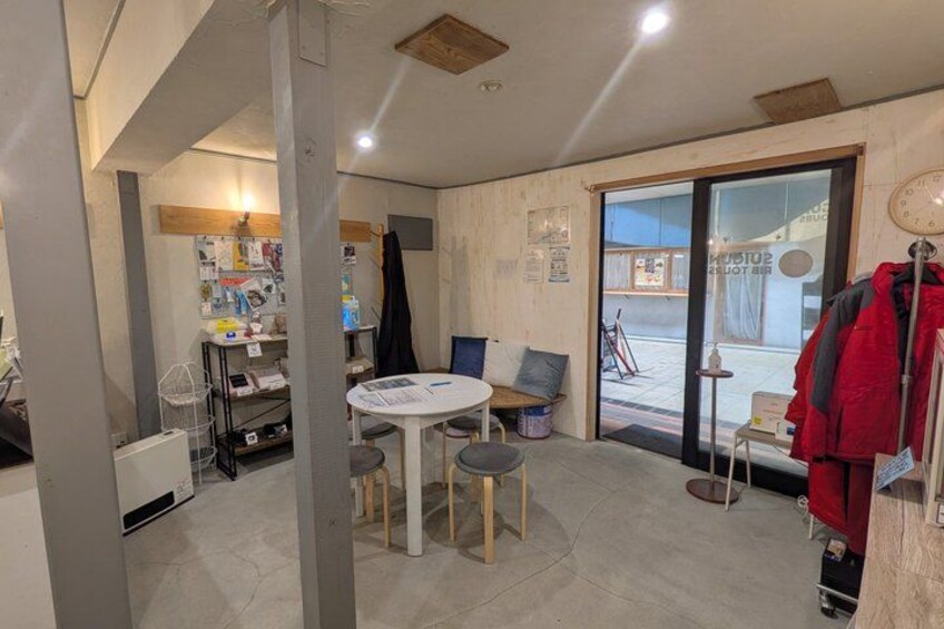 A room with a round table, chairs, a coat rack with a red jacket, and a door leading outside. 3