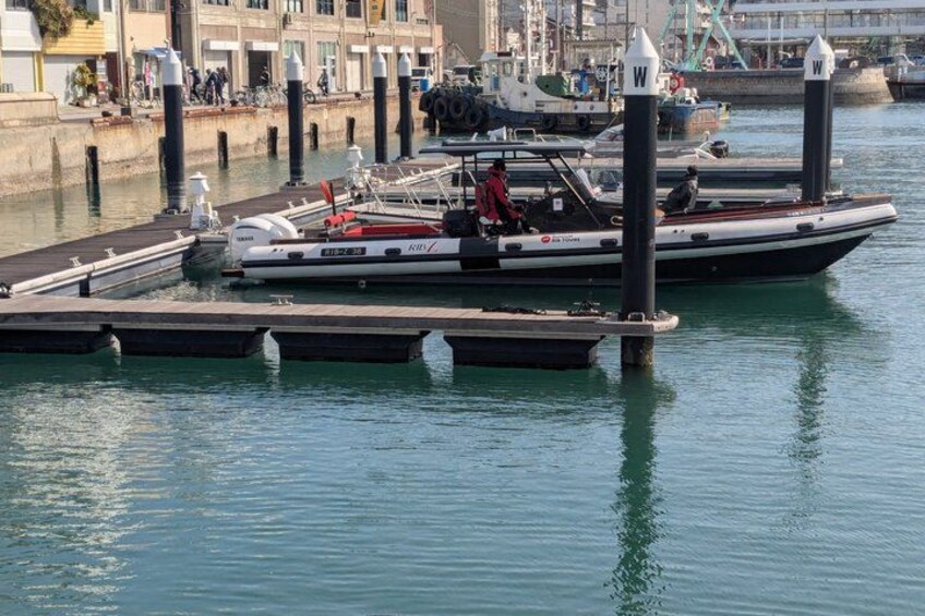 A marina with boats docked, a person on a boat, and a waterfront promenade. 2