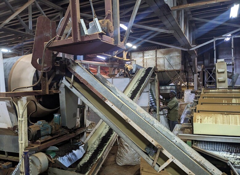 A large industrial machine with a conveyor belt system, metal structures, and a worker operating machinery. 2