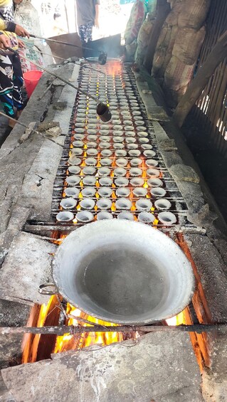 Una bandeja metálica sobre fuego abierto con un enrejado de moldes circulares. 5