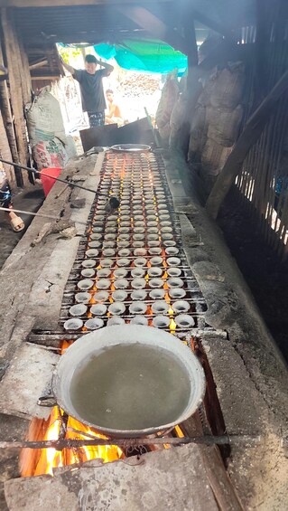 Un montaje de cocina tradicional con un fuego grande y varias ollas dispuestas en filas. 2