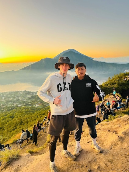 Two people standing on a hill with a mountain in the background. 3