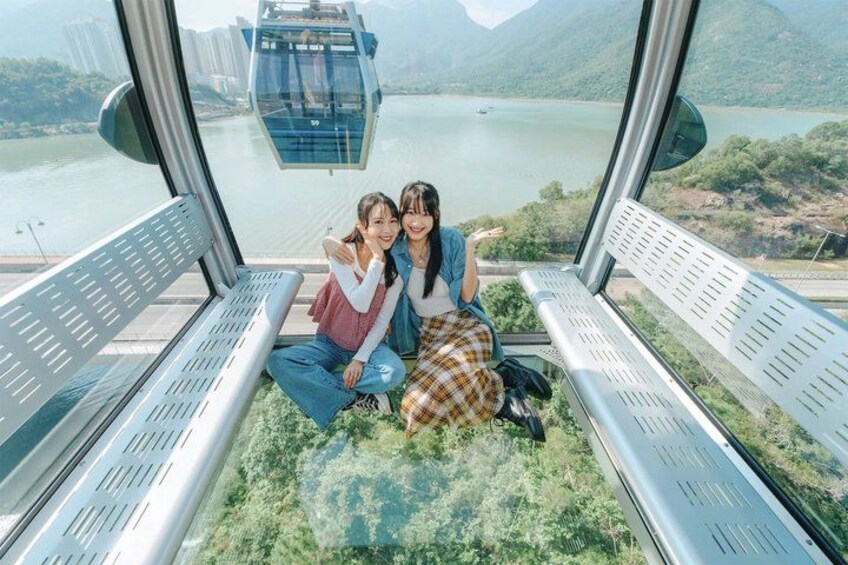 Two people sitting on a bench with a scenic view of a cable car and a lake. 3