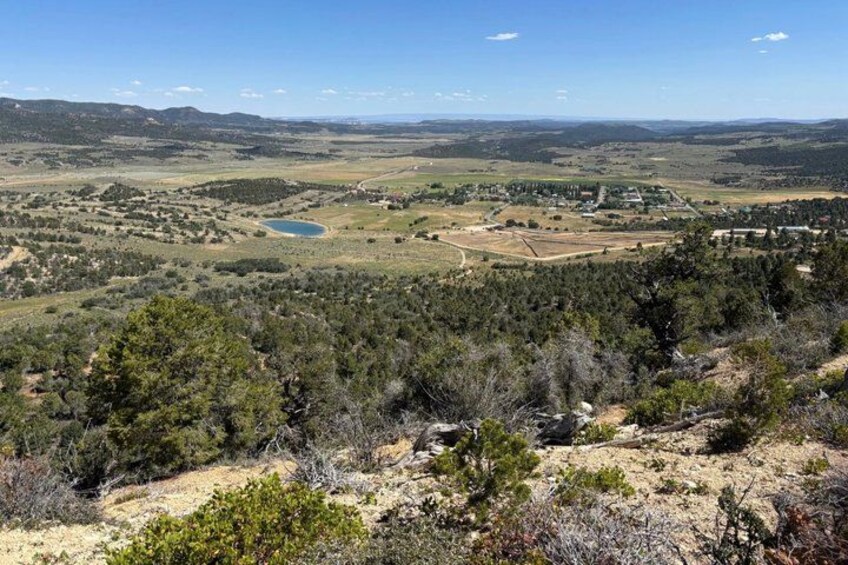 A mountainous landscape with a lake, forested areas, and a small settlement. 3