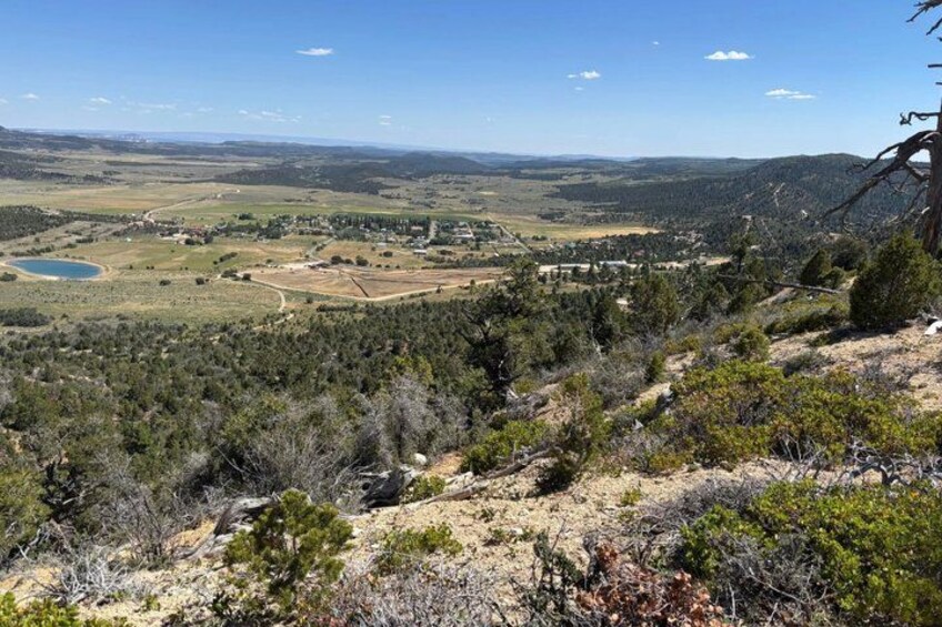 A mountainous landscape with sparse vegetation, a small lake, and distant buildings. 2