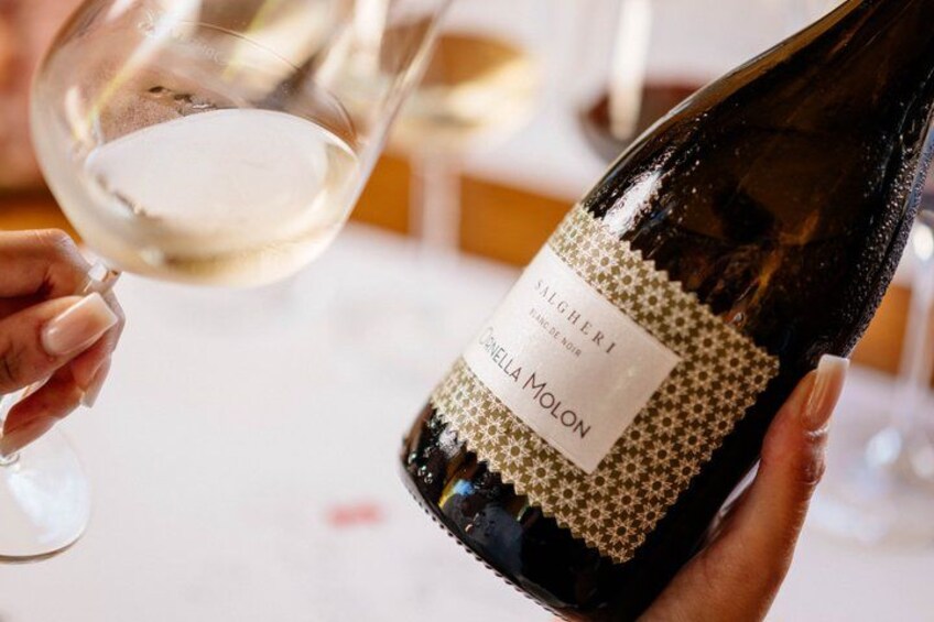 A person holding a wine bottle with a label and pouring wine into a glass. 5