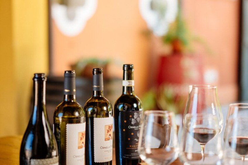 A row of wine bottles and glasses on a table. 1