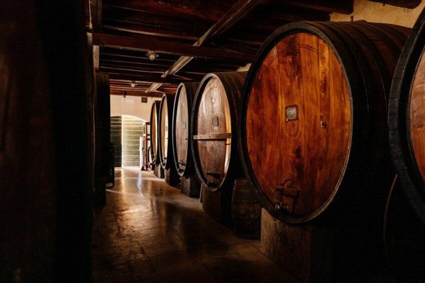 A row of wooden wine barrels in a dimly lit cellar. 2
