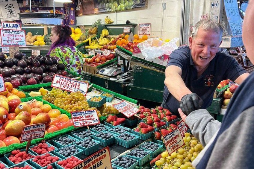 A fruit market with various fruits displayed in bins and boxes, and signs indicating prices and types of fruits. 2