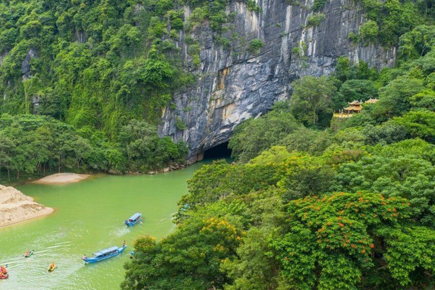 A river with boats, a cliff, and lush greenery. 4