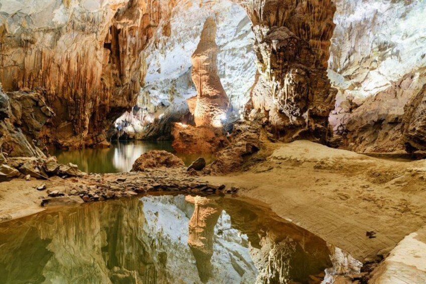 A cave with stalactites, a water pool, and a reflective surface. 5