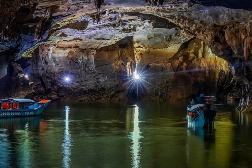 A cave with stalactites, a boat, and a person. 2