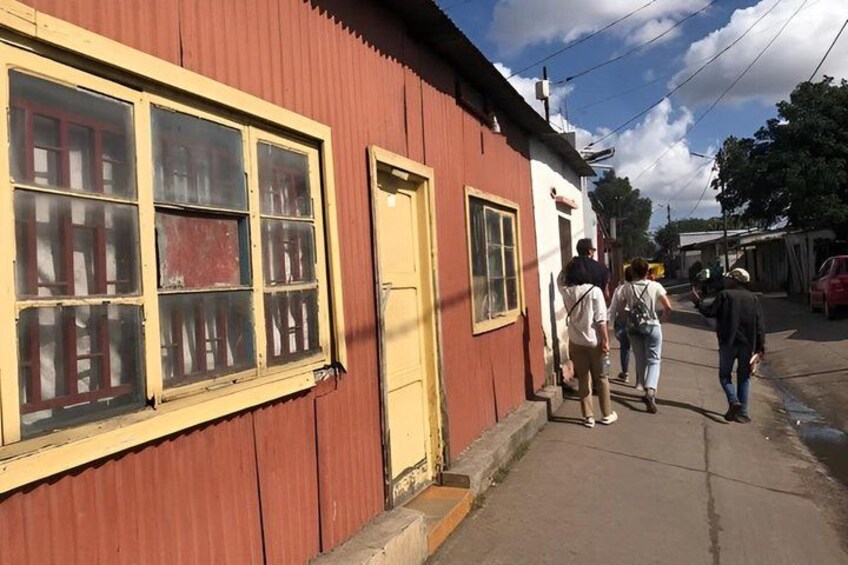 A red building with a yellow door and windows, a sidewalk, and people walking. 4
