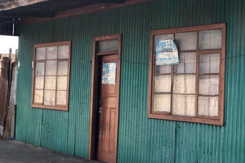 A corrugated metal building with two large windows and a wooden door. 3