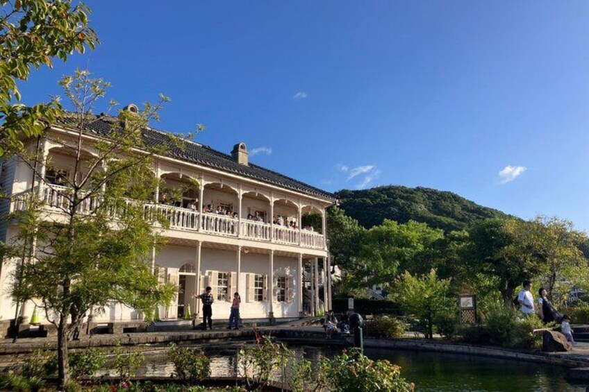 A two-story building with a balcony, surrounded by greenery and a body of water. 4