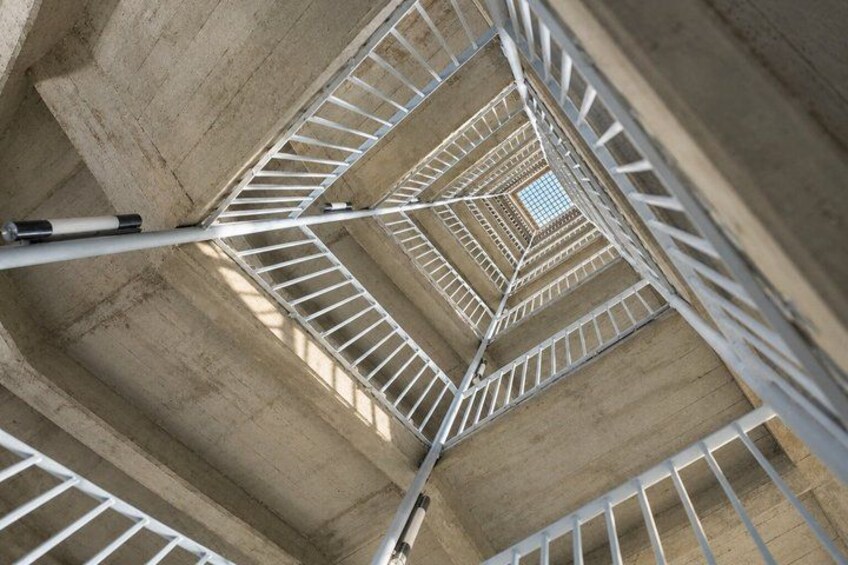 A spiral staircase with concrete walls and metal railings. 2