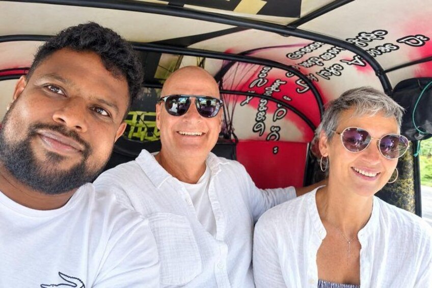 Three people seated in a vehicle with a red interior and a black roof. 1