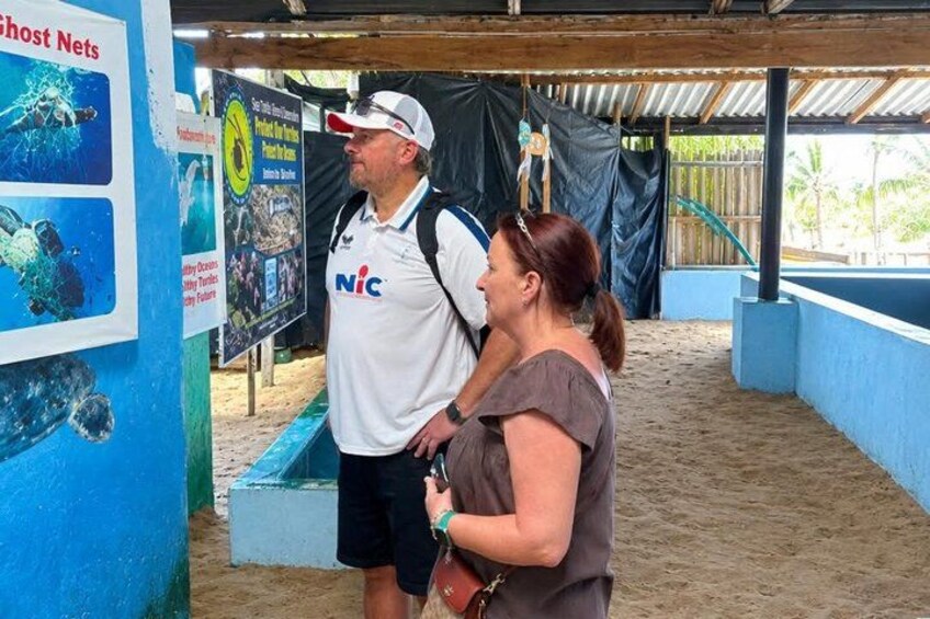 Two people standing in an outdoor exhibit area with informational posters and a blue wall. 4
