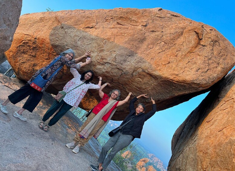 Un grupo de personas posando junto a una gran formación rocosa. 5