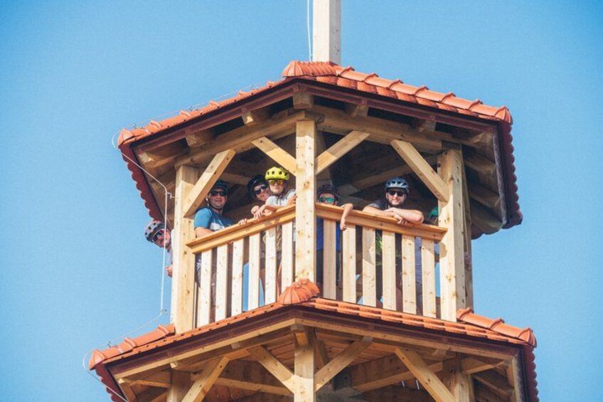 A wooden lookout tower with a red roof and a balcony. 3