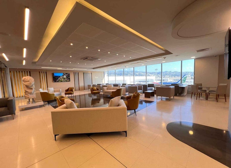 A spacious lounge with modern furniture, large windows, and a view of the cityscape. 1