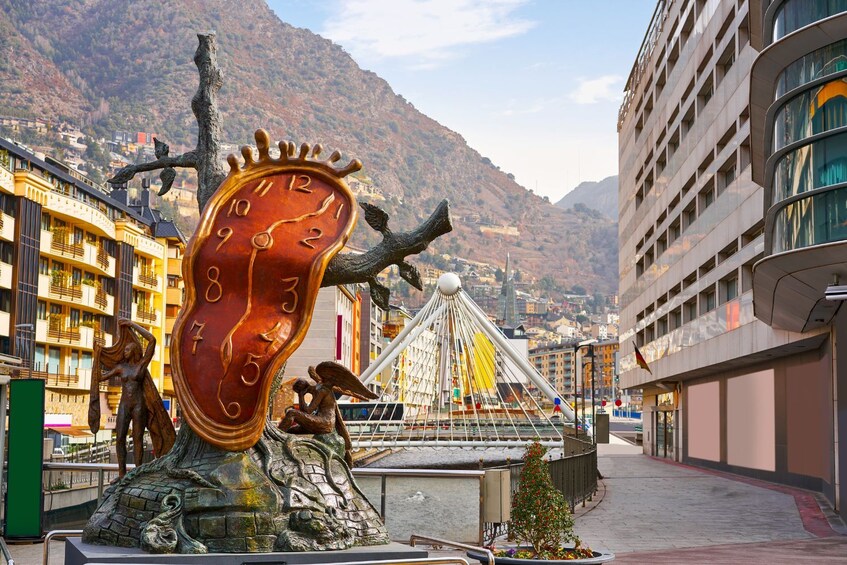 Una escultura de un reloj derritiéndose, una noria y un paisaje montañoso al fondo. 3