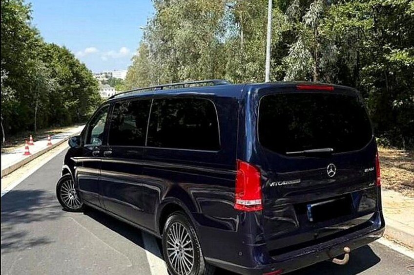 A dark blue van parked on a road with trees and a clear sky in the background. 2