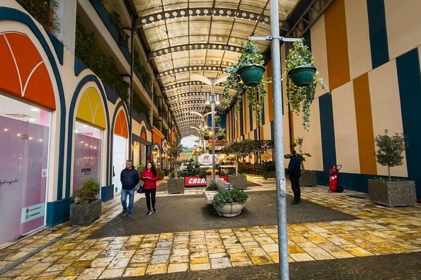 A covered shopping corridor with hanging plants, a fire hydrant, and a 'CASA' sign. 3