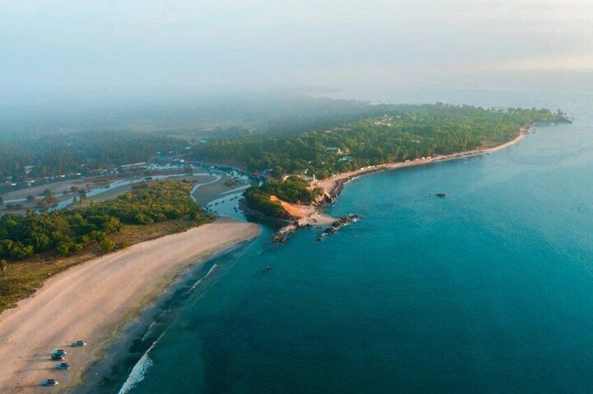 An aerial view of a coastal area with a sandy beach, a winding river, and a dense green forest. 2