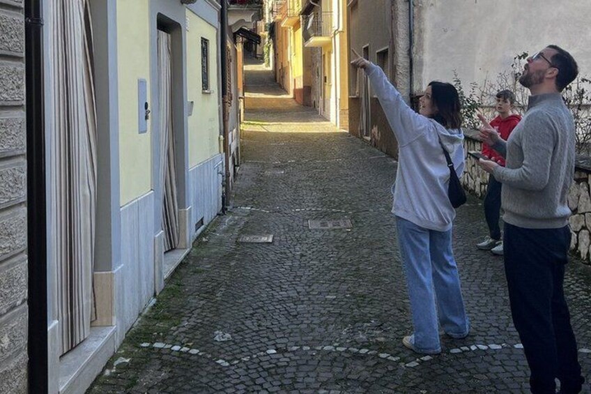 A cobblestone alley with buildings on either side, a person pointing towards the distance, and another person standing nearby. 4