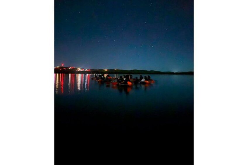 A calm lake at night with boats reflecting city lights. 2