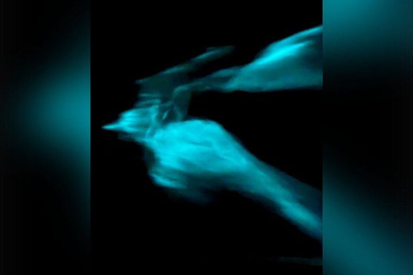 A blurred figure in motion, possibly a dancer, against a dark background. 5