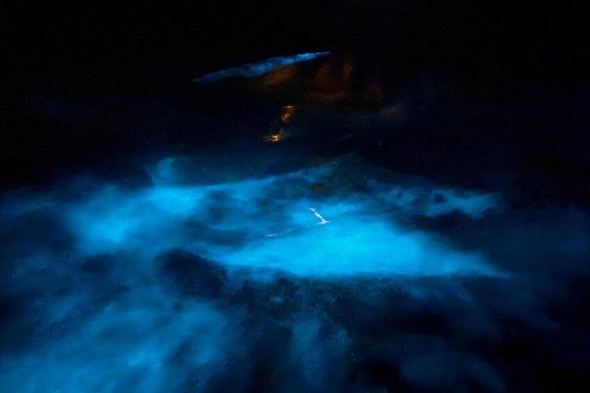 A blue-lit cave with a narrow passageway and a small light source. 5