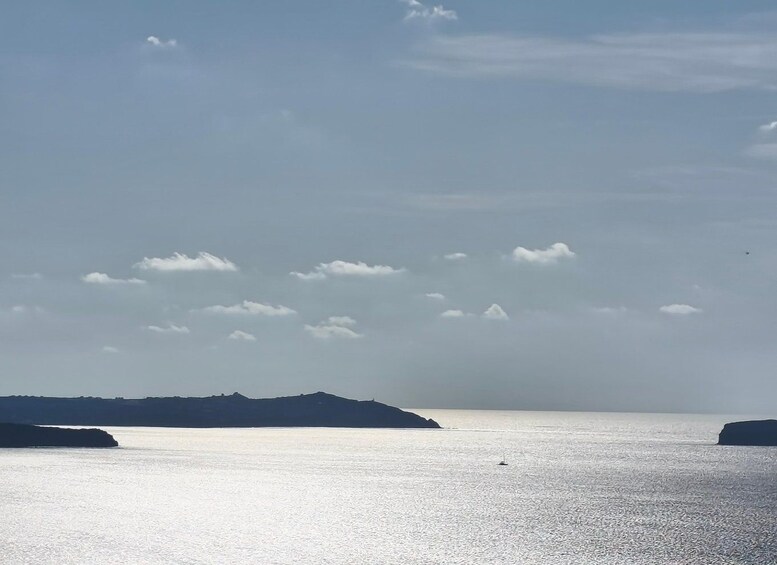A calm sea with a few clouds in the sky and distant landforms. 3